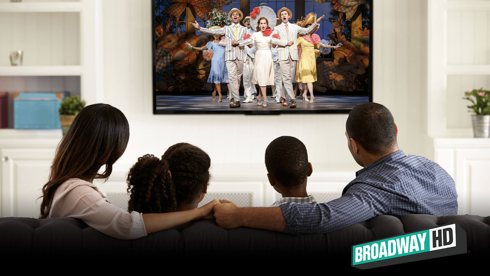 A family watching a Broadway musical recording on the television