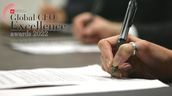Closeup of a CFO's hand signing a document. The 2022 Global CFO Excellence Awards logo is in the top left corner