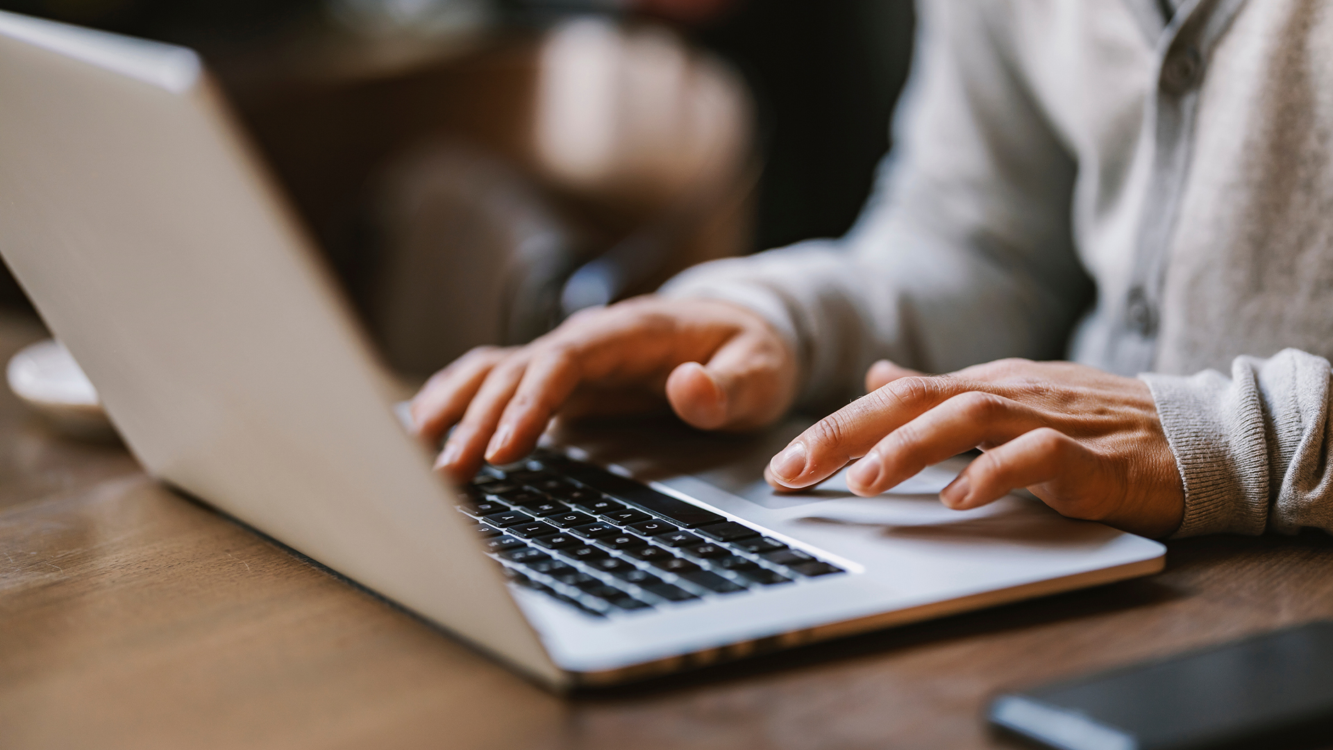 Close up of hands typing on a laptop in coffee shop.