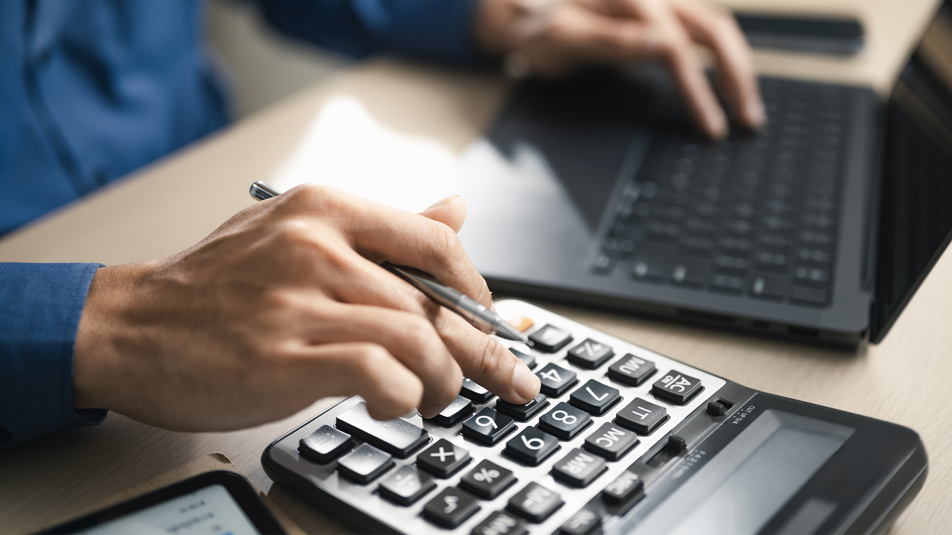 Business professional using calculator and laptop for budget planning and tax calculation, representing financial analysis, accounting management and personal finance control concept.